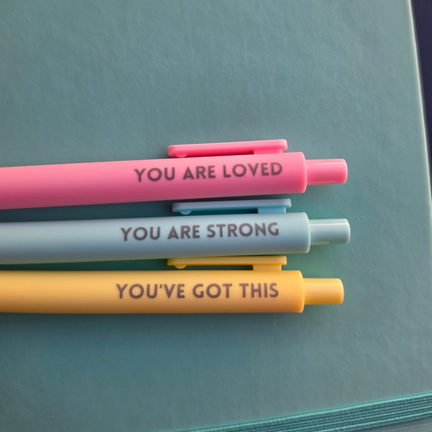 Three motivational pens with messages on a notebook